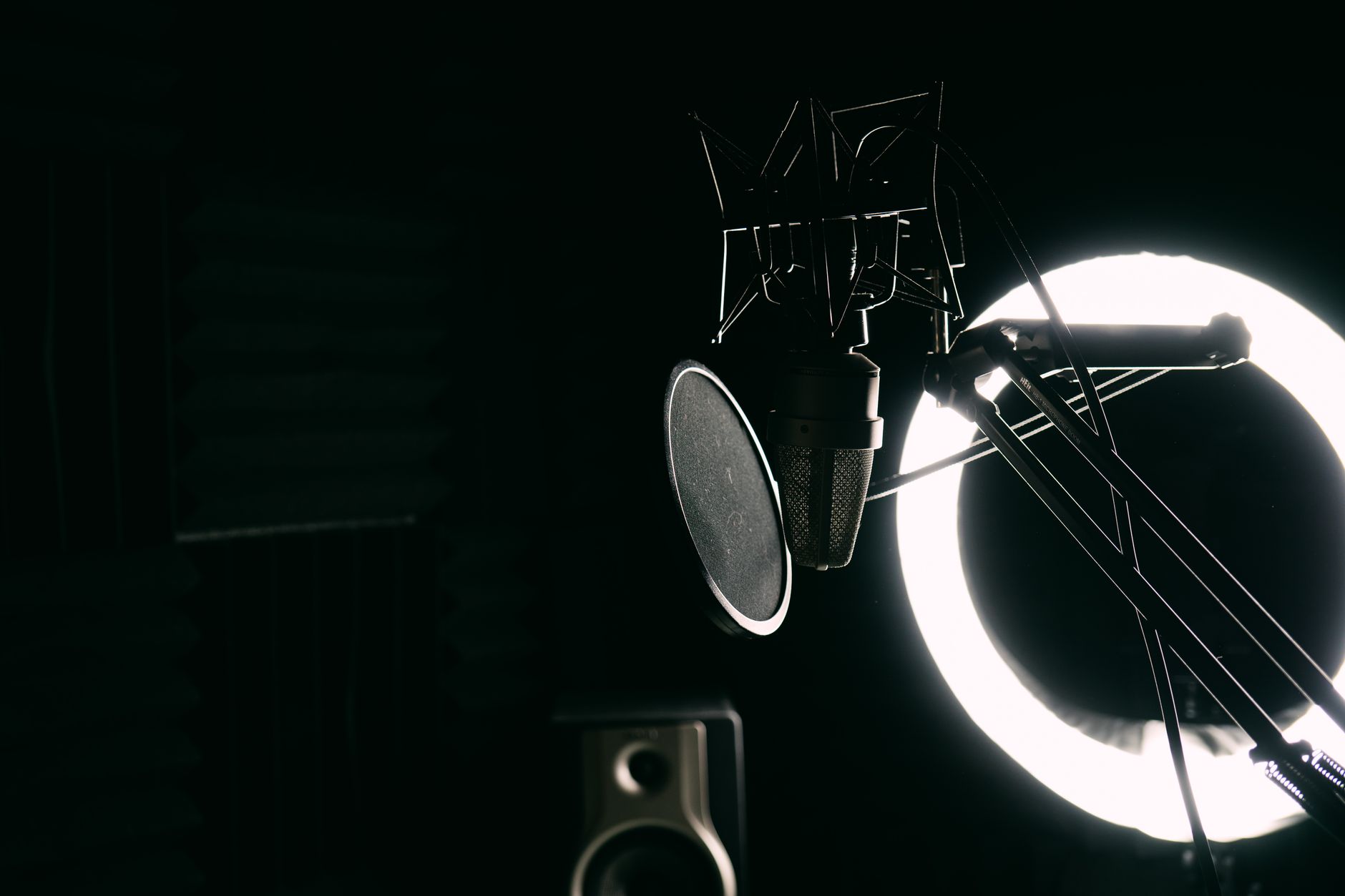 Microphone de studio avec filtre anti-pop et anneau lumineux dans une cabine d'enregistrement sombre